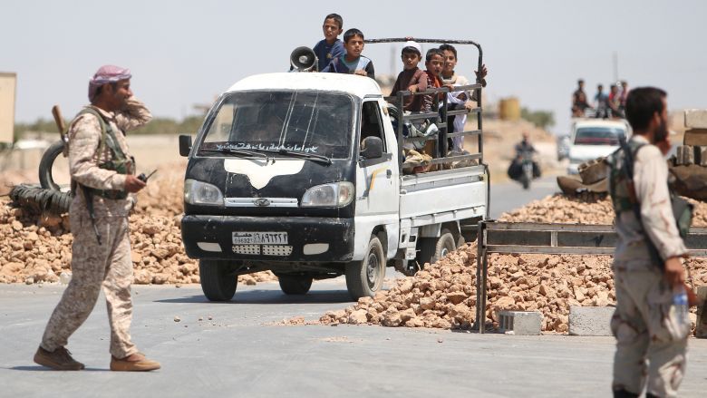 Syria Democratic Forces fighters man a checkpoint as civilians on pick-up trucks evacuate from the southern districts of Manbij city after the SDF advanced into it in Aleppo Governorate. The SDF quickly surrounded Manbij but the fight to take the