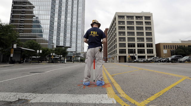 ASSOCIATED PRESS           Investigators work in the area of downtown Dallas that remains an active crime scene Saturday