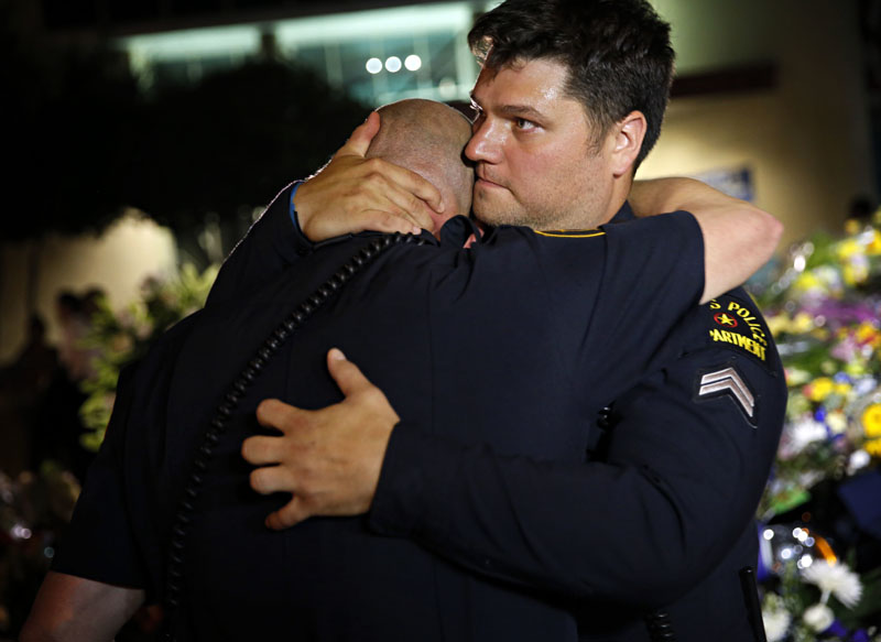 Dallas Police Department officers embrace as they visit a memorial in front of police headquarters in Dallas on Friday