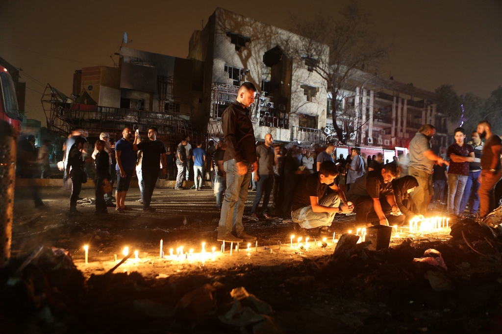 People light candles at the scene of a massive car bomb attack in Karada a busy shopping district where people were shopping for the upcoming Eid al Fitr holiday in the center of Baghdad Iraq Sunday