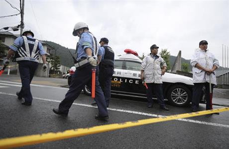 Police officers stand guard at the main gate of Tsukui Yamayuri-en a facility for the disabled where a number of people were killed and dozens injured in a knife attack in Sagamihara outside Tokyo Tuesday