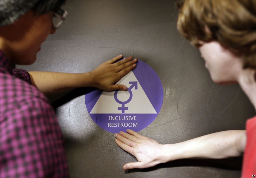 FILE- A new sticker is placed on the door at the ceremonial opening of a gender neutral bathroom at Nathan Hale high school in Seattle