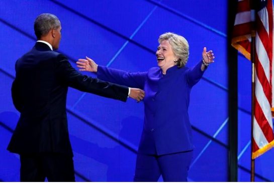 Democratic presidential nominee Hillary Clinton reaches for President Barack Obama as she steps on stage after President Obama's speech during the third day of the Democratic National Convention in Philadelphia, Wednesday