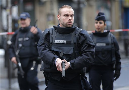 Police officers secure the perimeter near the scene of a fatal shooting which took place at a police station in Paris Wednesday Jan. 7 2016. French officials say a man armed with a knife was shot to death by officers at a police station in northern Par