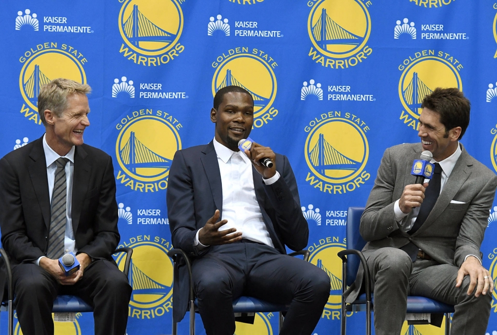 Head coach Steve Kerr of the Golden State Warriors sits with Kevin Durant and general manager Bob Myers