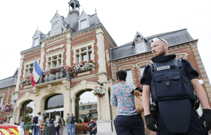 A French police officer stands guard by Saint-Etienne-du-Rouvray's city hall following a hostage-taking at a church in Saint-Etienne-du-Rouvray northern France on Tuesday that left a priest dead. — AFP