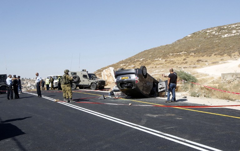 Israeli police look for evidences at the scene where Miki Mark was killed and three members of his family were wounded when a Palestinian terrorist opened fire at their car