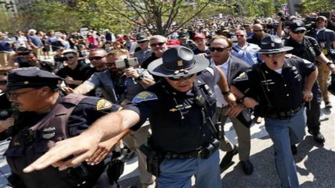 Alex Jones second from right an American conspiracy theorist radio show host is escorted out of a crowd of protesters after he said he was attacked in Public Square on Tuesday