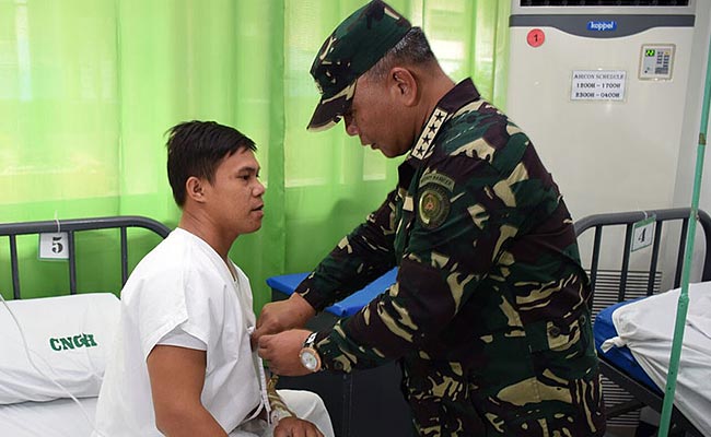 Chief of Staff Ricardo Visaya pins a medal to a wounded soldier at Cam Navarro General Hospital