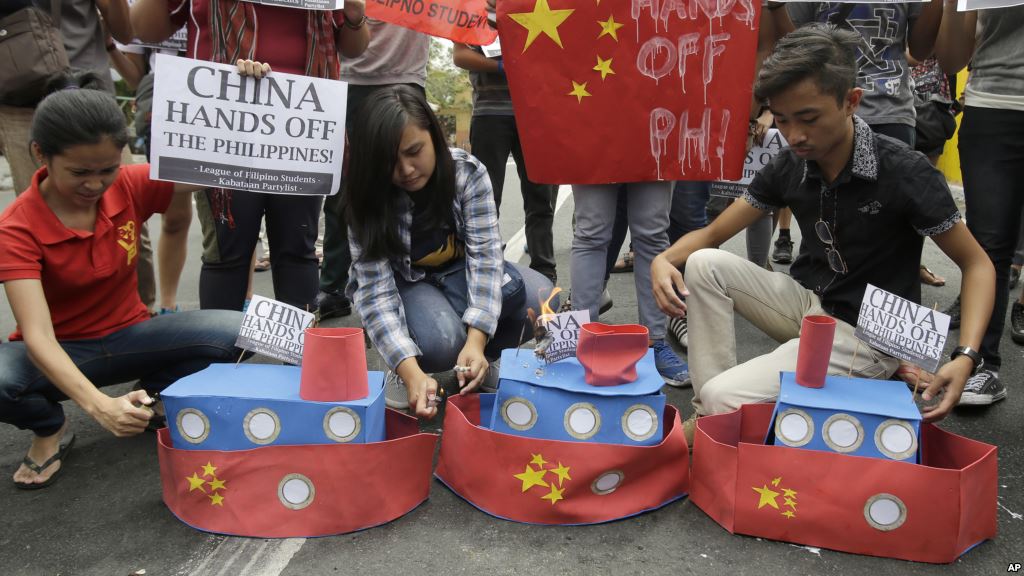 FILE- Filipino student activists set fire mock Chinese ships to protest recent island-building and alleged militarization by China off the disputed Spratlys group of islands in the South China Sea in Manila