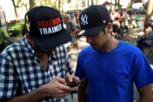 A man wears a Pokemon-themed hat as he plays the augmented reality mobile game'Pokemon Go by Nintendo in Bryant Park New York City