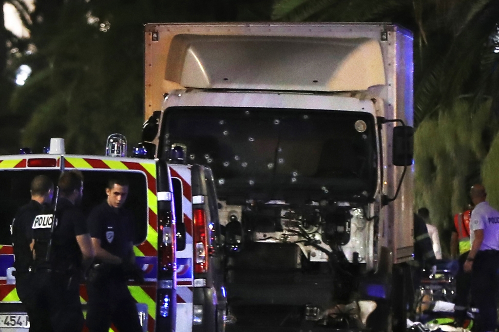 Police officers stand near a truck with its windscreen riddled with bullets