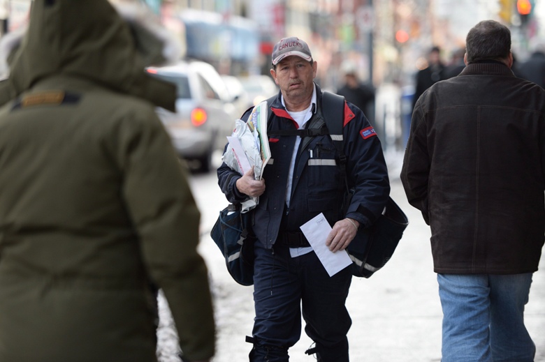 A mail carrier walks in Ottawa Wednesday Dec.11 2013