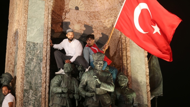 Supporters of the Turkish government sit on a statue of the founder of modern Turkey during a Wednesday demonstration in Istanbul against the July 15 failed coup attempt. Turkish President Recep Tayyip Erdogan has overseen the dismissal of 50,000 workers