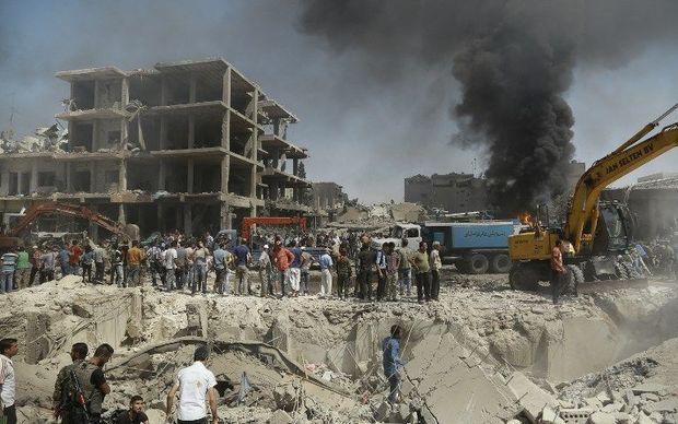 Residents gather at the site of a bomb attack in Syria's northeastern city of Qamishli