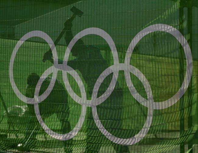 Workers secure a fence at Olympic Park as they make preparations for the upcoming Rio Olympics in Rio de Janeiro Brazil Wednesday