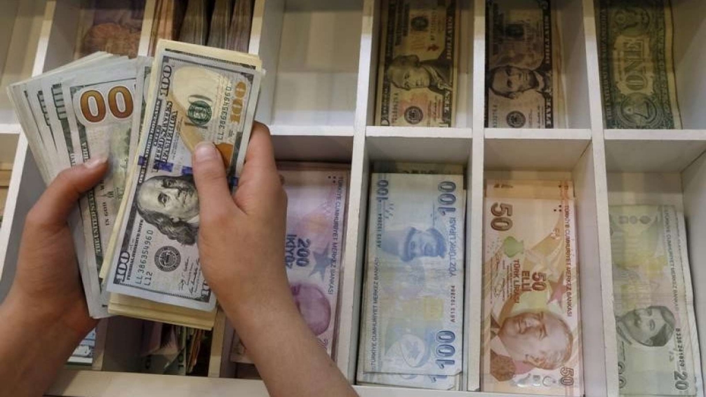 A money changer counts U.S. dollar bills with Turkish lira banknotes in the background at an currency exchange office in central Istanbul Turkey