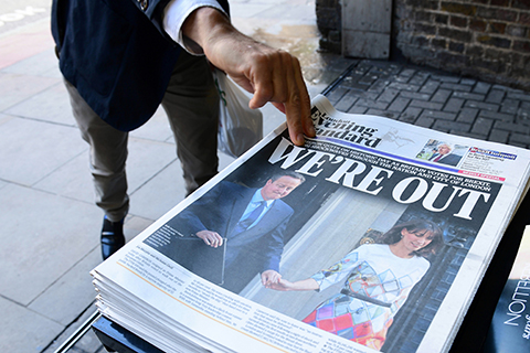 TOPSHOT- A man takes a copy of the London Evening Standard with the front page reporting the resignation of British Prime Minister David Cameron and the vote to leave the EU in a referendum showing