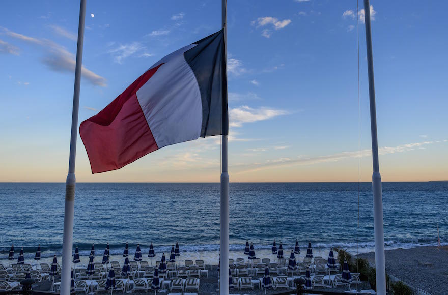 A French flag flies at half mast at an empty beach on the Promenade des Anglais in Nice France