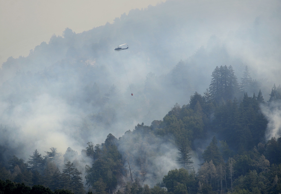 A helicopter flies in to make a water drop Saturday on a ridge above Rancho San Carlos in Carmel Valley Calif