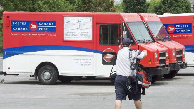 A postal worker walks past Canada Post trucks at a sorting centre in Montreal Friday