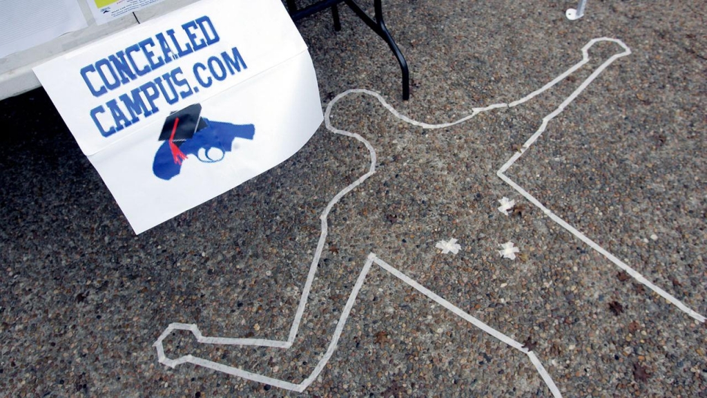 Signs and a replica of a crime scene draw attention to a pro-carry booth on the campus of Texas State University San Marcos