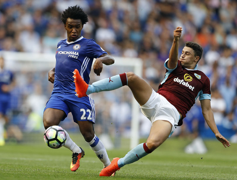 Chelsea's Willian and Burnley's Matthew Lowton challenge for the ball during the English Premier League soccer match between Chelsea and Burnley at Stamford Bridge in London on Saturday