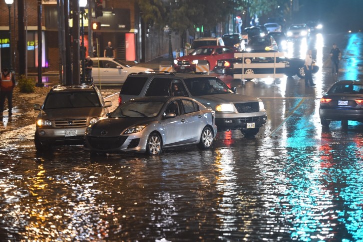 Authorities stand near a blocked off road as floodwaters rise in Kansas City Mo. Friday Aug. 26 2016