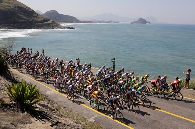 The peleton rides by Grumari beach during the men's cycling road race final at the 2016 Summer Olympics in Rio de Janeiro Brazil Saturday Aug. 6 2016