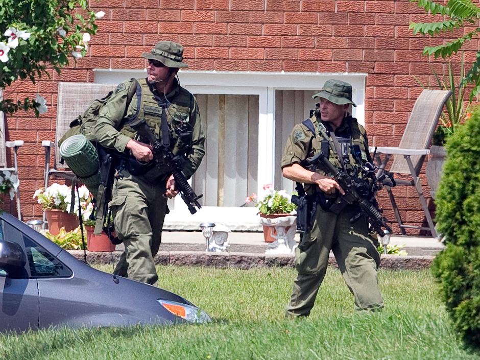 Armed OPP officers walk near the house where terrorism suspect Aaron Driver was killed during a police operation on Wednesday in Strathroy Ont