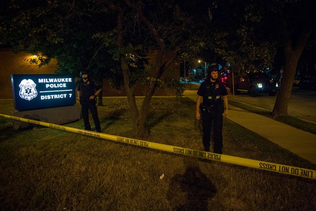 Police officers stand guard at the District 7 police station as angry crowds took to the streets for a second night to protest an officer-involved killing