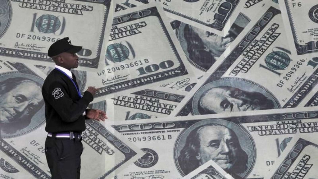 A security guard walks past a montage of U.S. dollar bills outside a currency exchange bureau in Kenya's capital Nairobi