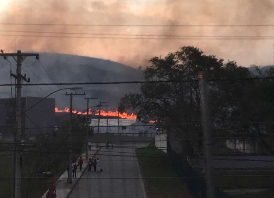 A fire burns roughly 10 miles from the Olympic field hockey venue during the 2016 Summer Olympics in Rio de Janeiro Brazil Monday Aug. 15 2016. High winds blew smoke and ash onto the playing surfaces before the evening session which included two matc