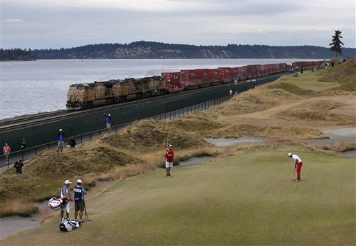 Rickie Fowler lines up his putt on the 17th hole as a train goes by during the first round of the U.S. Open golf tournament at Chambers Bay on Thursday