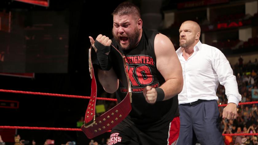 Kevin Owens celebrates his newly won WWE Universal Championship as Triple H looks