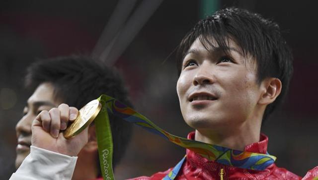 Kohei Uchimura of Japan holds up his gold medal after Japan won the men's team final