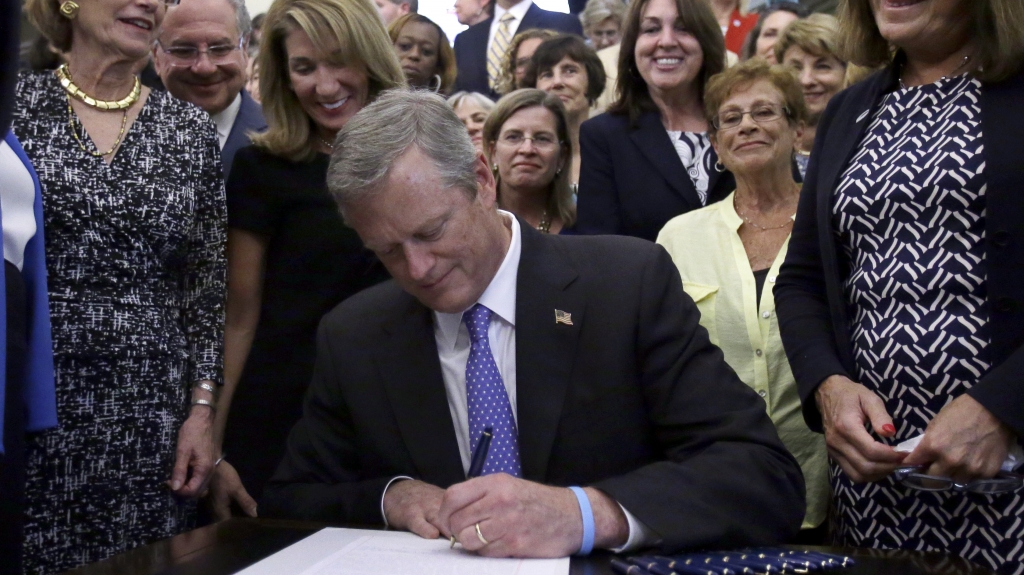 Massachusetts Gov. Charlie Baker signs a pay equity act into law at the Massachusetts State House on Monday in Boston