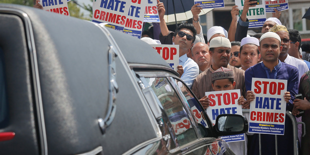 Mourners hold signs protesting against the killings of an imam and his assistant in New York during the funeral services for both men