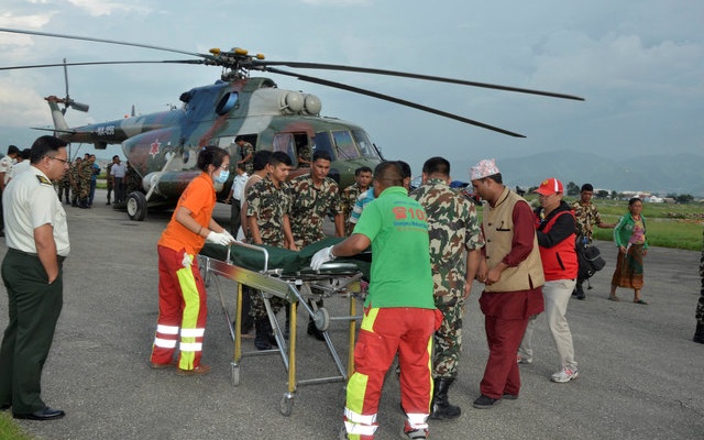 Nepalese army personnel assist a victim of a bus accident after being airlifted from Birtadeurali in Kavre to Kathmandu Nepal