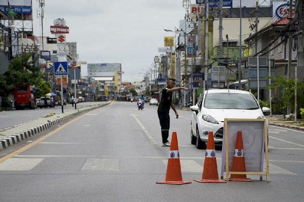 PENNY YI WANG						Credit AP				Police direct traffic on a mostly deserted street Friday after several bombings in Hua Hin a normally bustling tourist town