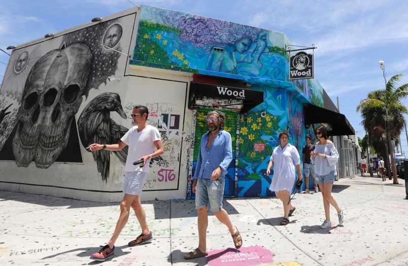 A group of visitors walk by an establishment in the Wynwood area of Miami Friday Aug. 5