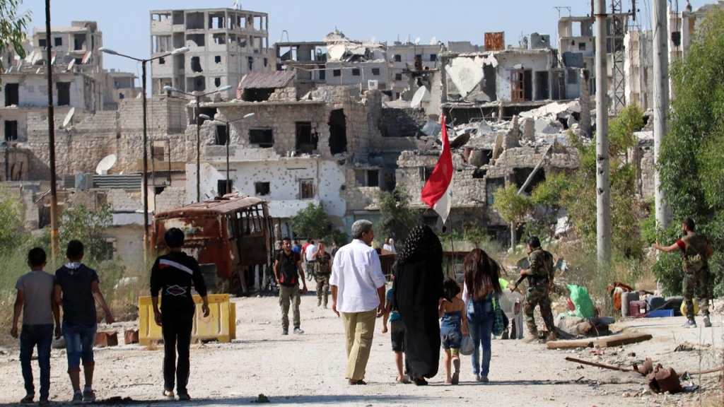 Syrian government forces secure a street as civilians come back to the neighbourhood of Bani Zeid on Aleppo's northern outskirts