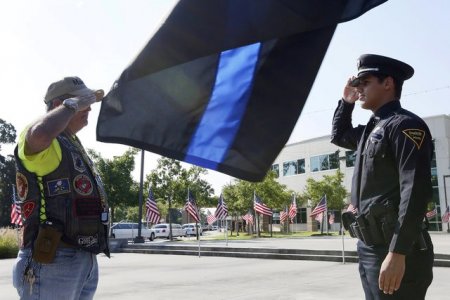 A law enforcement officer and a veteran salute one another at a funeral service for police officer Matthew Gerald at Healing Place Church in Baton Rouge Louisiana