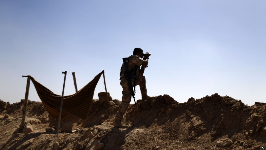 Kurdish Peshmerga fighter uses binoculars to check on Islamic State group's positions on the outskirts of Makhmour 300 kilometers north of Baghdad Iraq