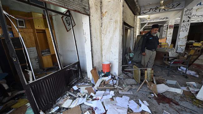 A Pakistani police officer inspects the site of a suicide bomb attack at a district court in Mardan