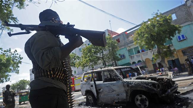 A Somali soldier is seen next to the burned-out wreckage of a car targeted in a bomb attack in Mogadishu Somalia