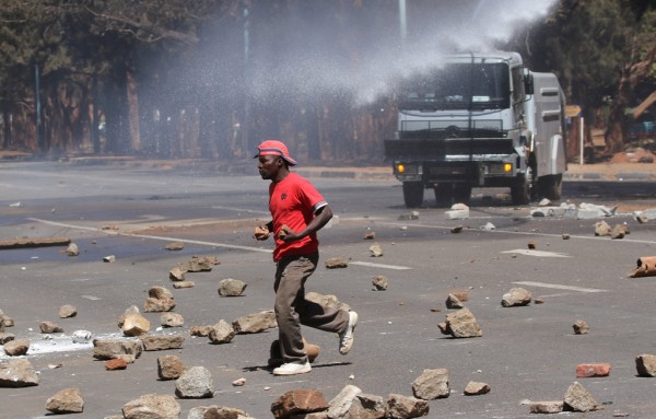 A man runs from a water cannon as opposition party supporters clash with police in Harare Zimbabwe 26 August 2016