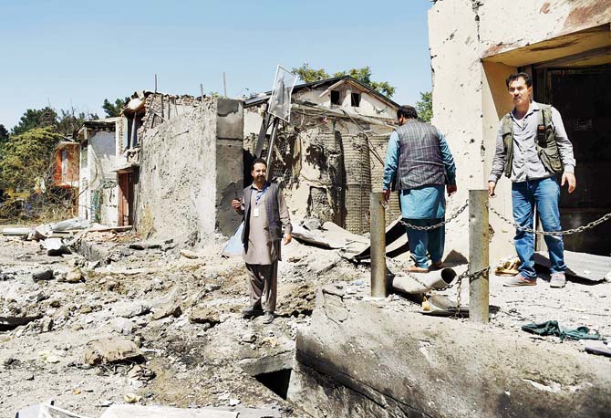 Afghan security personnel and residents walk at the site of a car bomb blast that targeted the CARE International compound at Shar-e Naw in Kabul. Pic  AFP