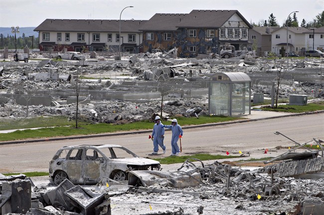 Workers put out markers around a devastated area of Timberlea in Fort Mc Murray Alta on Thursday