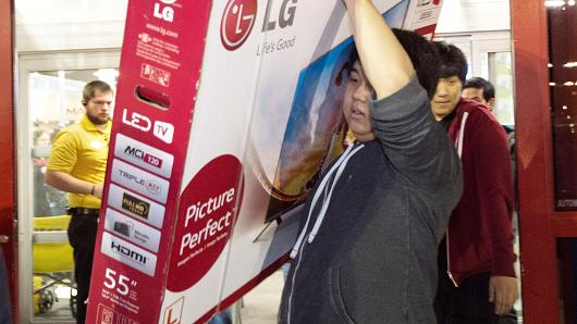 A man carries a big screen TV out of a Best Buy in Fairfax Virginia